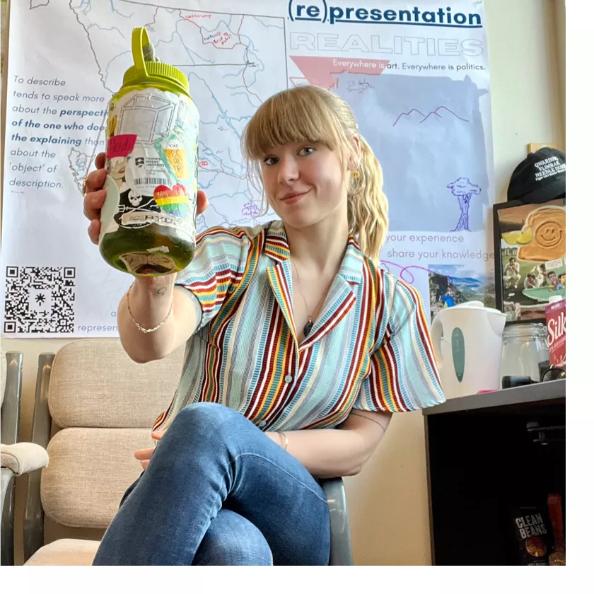 A women sitting on a couch holding her reusable water bottle.