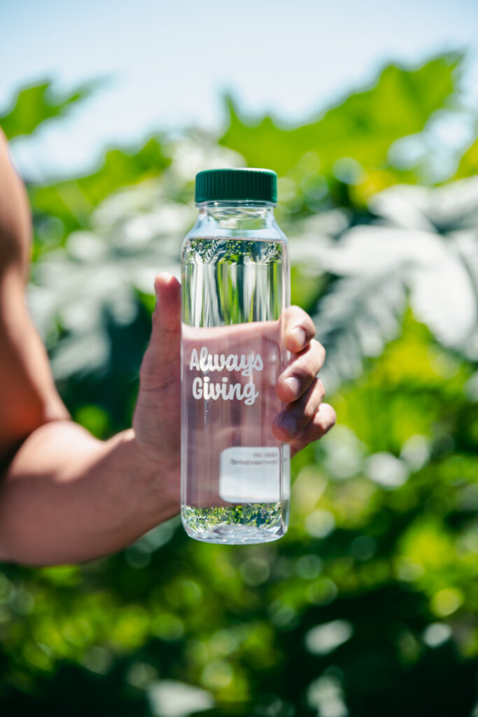 Hand holding Fill it Forward Cupanion Bottle with Always Giving printed on the bottle with a QR code