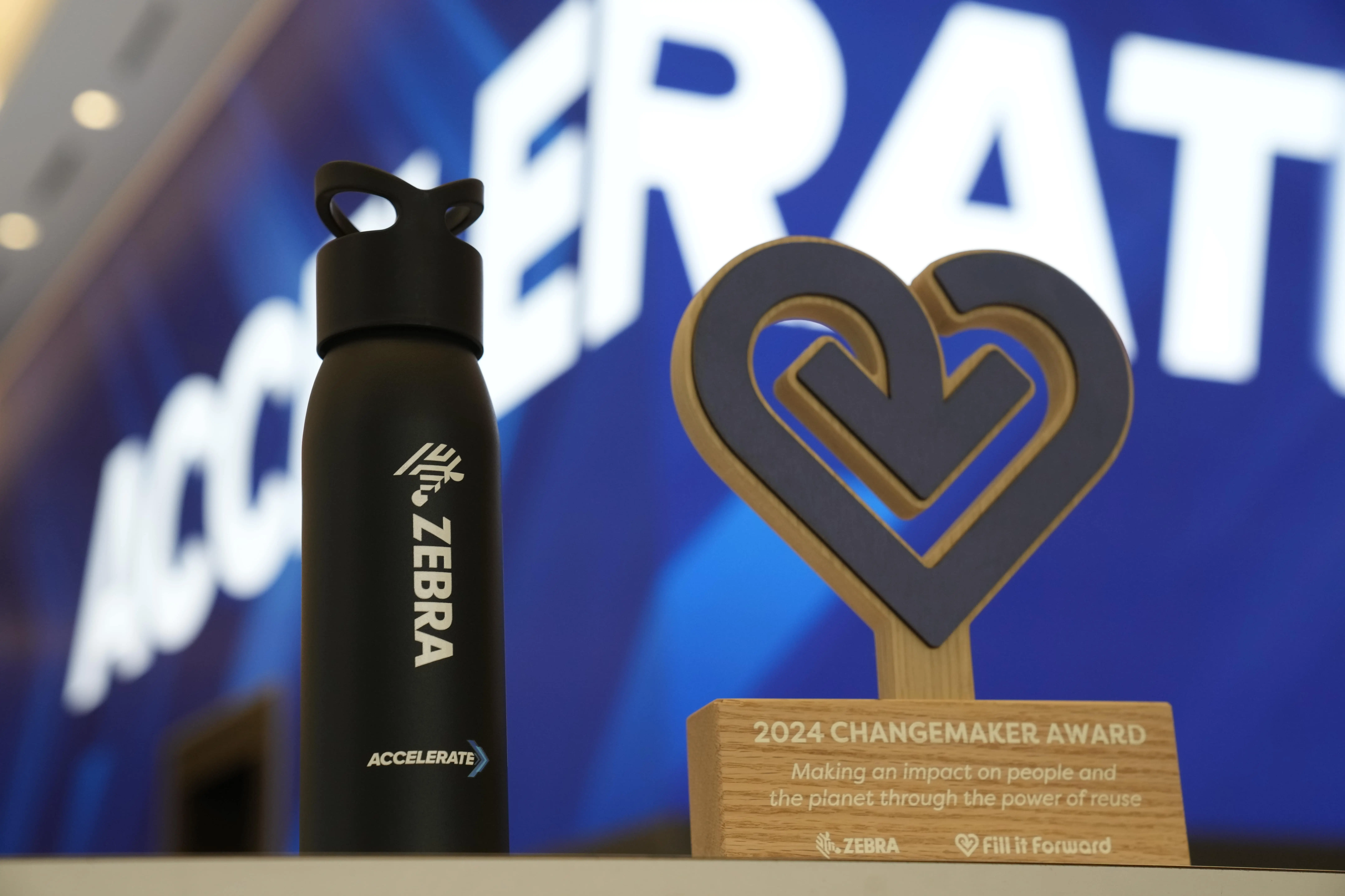 A Cupanion Aluminum bottle with the Zebra Logo in it next to a Fill it Forward 2024 Changemaker Award